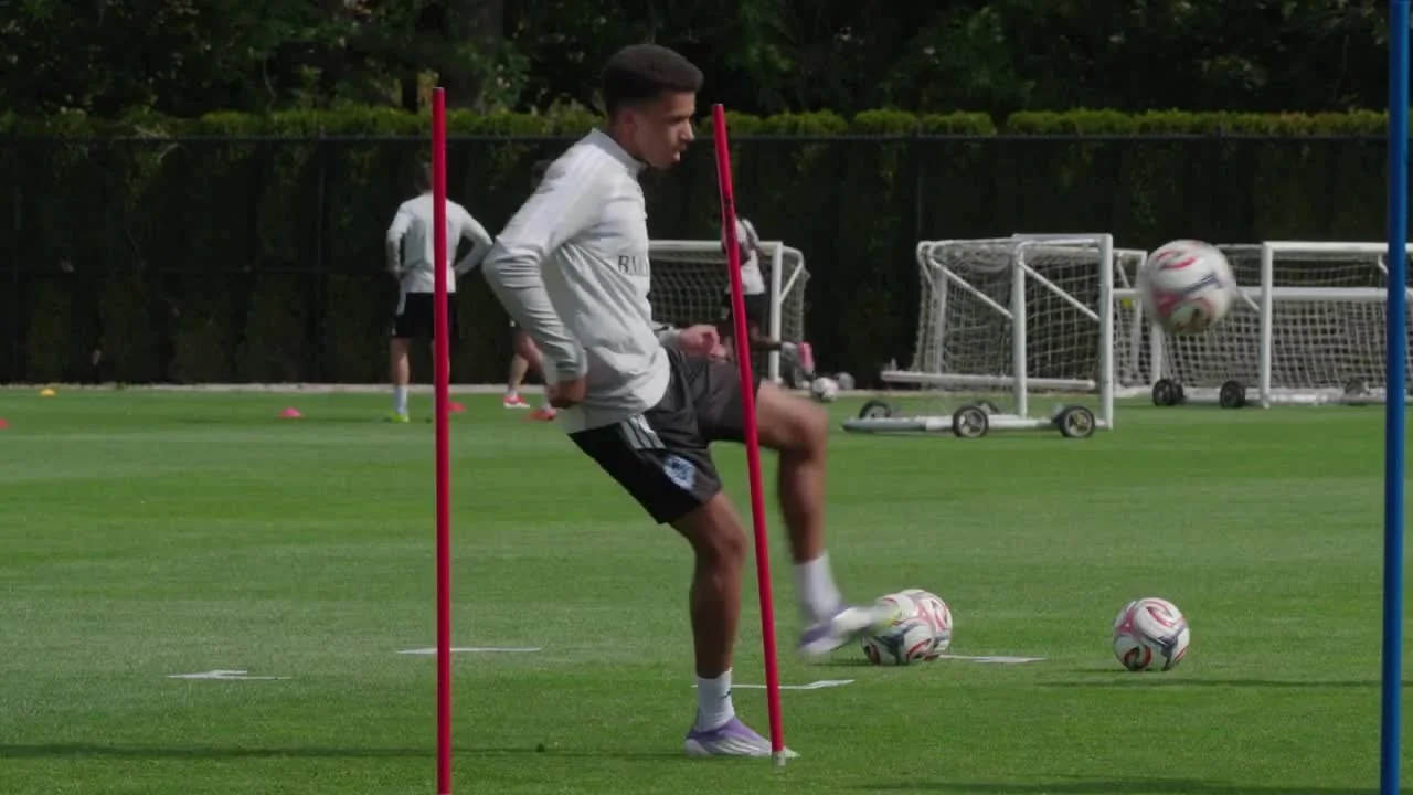 A Vancouver Whitecaps player controlling a ball between training poles with small goals behind him