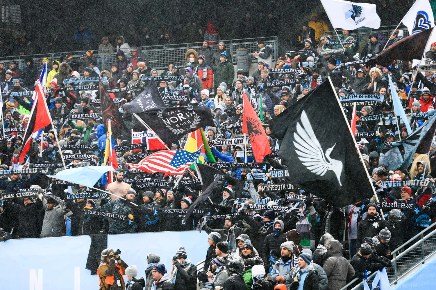 Minnesota United supporters bundled in winter clothing with scarves and flags during the snowy 2017 home opener at TCF Bank Stadium